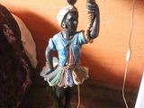 a statue of a man holding a tea pot on a table