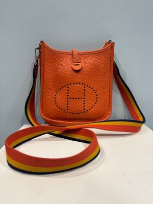 an orange purse with a yellow and red ribbon around it