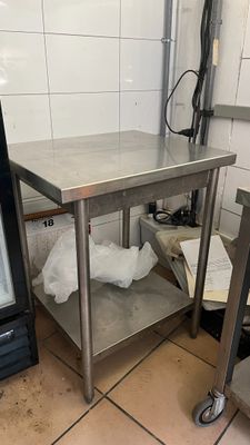 une table en acier inoxydable avec une porte en verre dans une cuisine