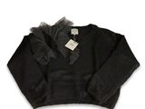 Le pull est noir et comporte un volant en tulle autour du cou.