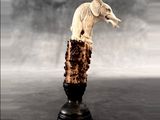 a statue of a dog that is on top of a piece of wood