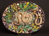 a decorative plate with a snake on it on a stand