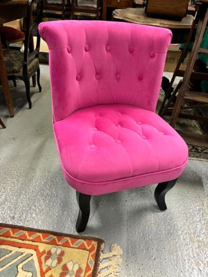 une chaise rose qui se trouve au milieu d'une pièce