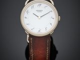 une montre à cadran blanc avec un bracelet en cuir marron, posée sur un fond noir
