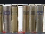 six books are lined up in a row on a black surface