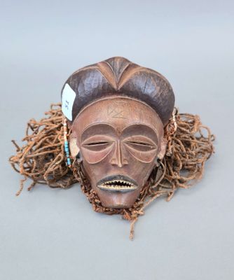 un gros plan d'un masque en bois orné de dreadlocks