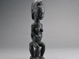 une sculpture noire représentant une femme tenant un bébé dans ses bras