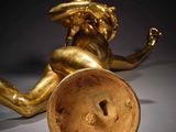 an antique gold figurine of a woman with a hat on her head sitting on a table