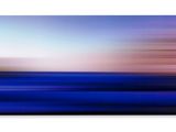 a blurry photo of a blue ocean with a pink sky in the background