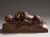 statue en bronze représentant un lion posé sur une plaque, tenant une boule entre ses pattes