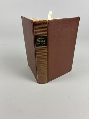 un vieux livre à la couverture marron posé sur une table blanche