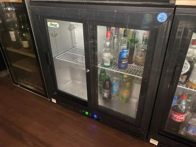 bottles of alcohol are lined up in a glass case in a bar