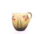 a small vase with red flowers on it on a white surface