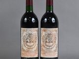 two bottles of red wine sitting next to each other on a table