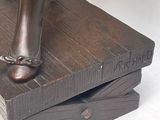 a bronze statue of a woman standing on top of a stack of books