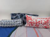 three pillows on a bed with a blue and red cover