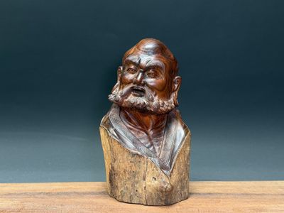 an old wooden bust of a man with a beard on a wooden table