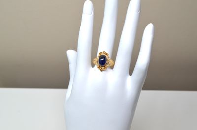 a ring on a mannequin hand with a blue stone