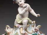 a clock with a figurine of a baby on top of it