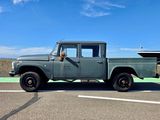 un camion vert garé sur un parking, avec un bateau en arrière-plan