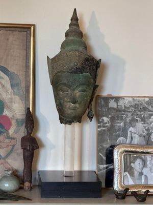 a picture of a buddha head on a shelf next to a picture of a man