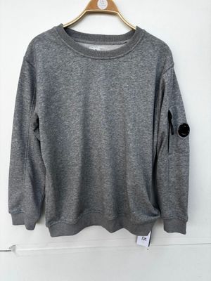 a grey sweater hanging on a hanger on a white wall