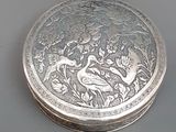 une boîte en argent ornée d'un oiseau, posée sur une table