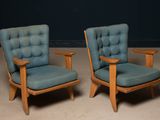 une paire de fauteuils rembourrés bleus avec des accoudoirs et des pieds en bois