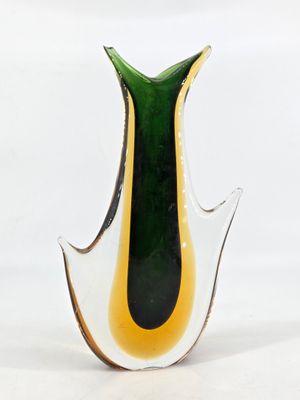 a green and yellow vase sitting on a white surface