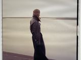 a woman standing on the beach looking out at the water