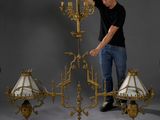 an image of a man standing in front of a chandelier with three lamps