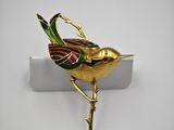 an image of a gold bird broochle on a white surface