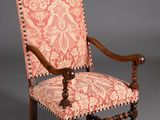 une vieille chaise dont le dossier est recouvert de tissu rose et blanc