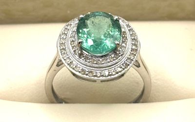 une bague ovale sertie d'une émeraude et de diamants, présentée dans un coffret blanc