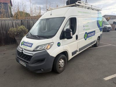une camionnette blanche garée sur un parking, près d'une clôture