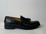 a pair of black loafers with tassels on them