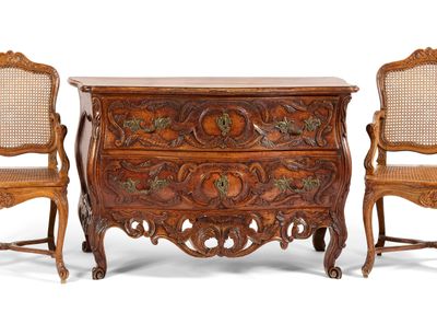 two chairs and a chest of drawers with carvings on the sides