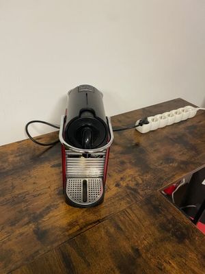 a coffee maker sitting on a wooden table next to a wall
