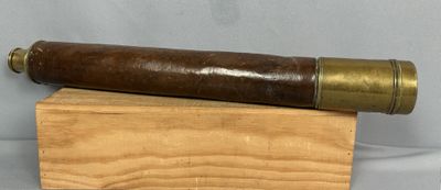 un vieux télescope posé sur un bloc de bois, sur fond blanc
