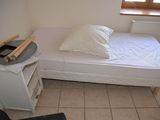 a small bed in a small room with a white sheet on it