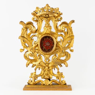 a gold clock with a red glass in the middle
