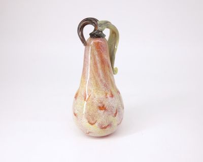 un petit vase en verre muni d'une anse, posé sur une surface blanche