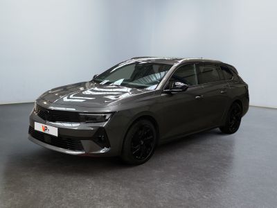 Une voiture grise est garée dans une pièce aux murs blancs.