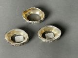 three silver plated objects on a gray surface with a square object in the middle