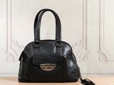 black leather handbag sitting on a table in front of a wall