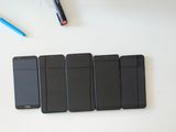 several cell phones are lined up on a table with pens and markers