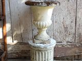 a white vase sitting on top of a stone pedestal