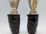 two silver vases sitting on top of each other on a white surface