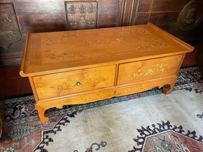 a wooden chest with two drawers and a rug on the floor