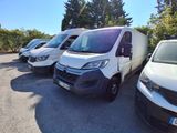 plusieurs fourgonnettes blanches garées sur un parking, avec des arbres en arrière-plan